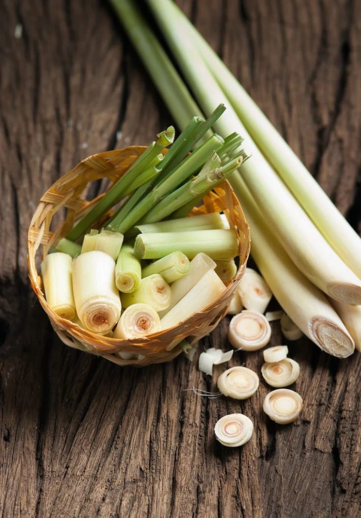 ChatGPT said: Fresh lemongrass stalks with vibrant green leaves, placed on a wooden surface, highlighting their natural texture and aromatic qualities.